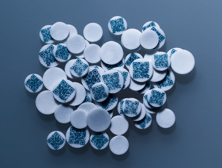 White 3D screen-printed tablets, many with a blue QR code printed into the surface